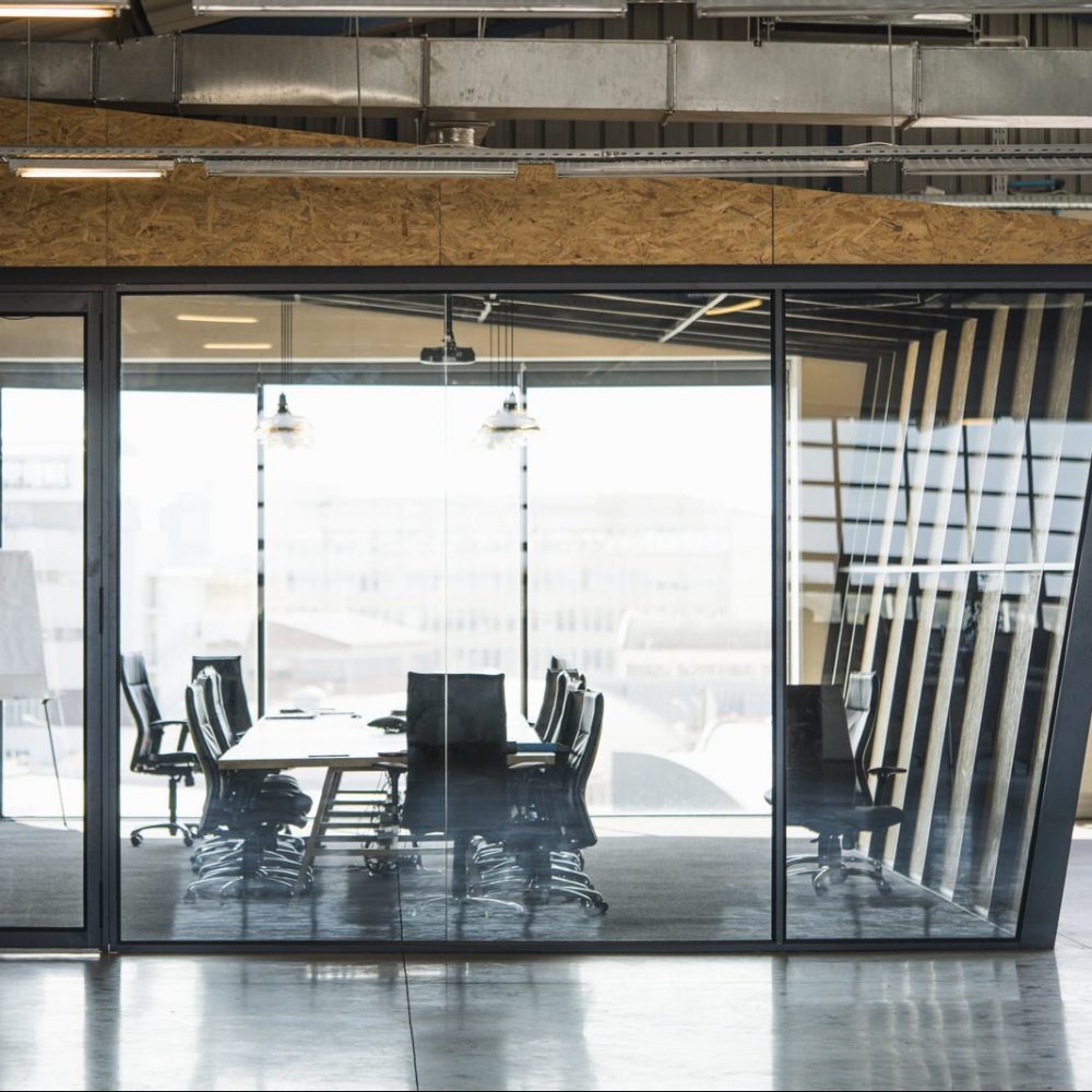 A photo of chairs and table in board room seen through glass. Conference room in creative office. Interior of modern workplace.